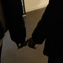 a man and a woman are holding hands in the dark .