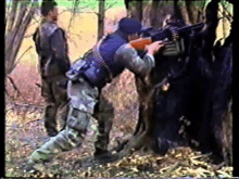 a man in a blue vest is aiming a gun at another man