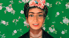 a woman with a flower crown on her head is standing in front of a green floral background