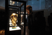 a man looking at a gold trophy in a glass case