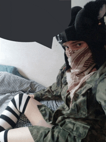 a person wearing a mask and striped knee high socks sits on a bed