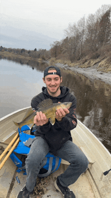 a man is sitting in a boat holding a fish in his hands