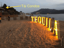 a sign on a beach that says tequila is lit up