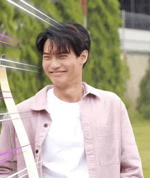 a man wearing a pink shirt and a white shirt smiles