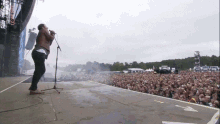 a man singing into a microphone in front of a crowd at a concert with a sign that says ' coca cola '