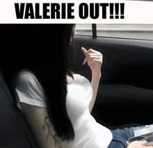 a woman in a white shirt is sitting in the back seat of a car with the words valerie out below her