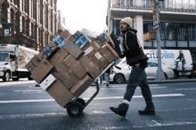 a man is pushing a cart filled with boxes down a city street .