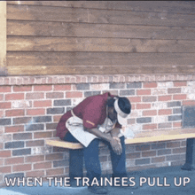 a man sits on a bench in front of a brick wall with the words when the trainees pull up below him