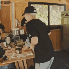 a man in a black shirt is standing in a messy kitchen with a box that says thom on it