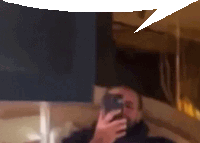 a blurry picture of a man holding a cell phone with a speech bubble above him