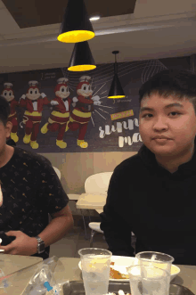 a boy sitting at a table in front of a jollibee advertisement