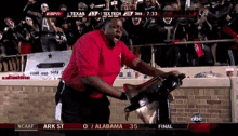 a man in a red shirt stands in front of a crowd watching a football game between texas and tex tech