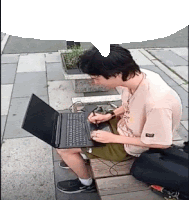 a young man is sitting on a bench using a laptop