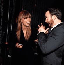 a man in a suit and a woman in a black jacket are laughing together