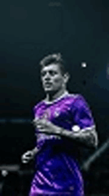 a man in a purple shirt is running on a dark background .