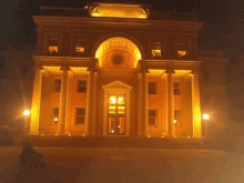 a large building is lit up at night and a person in a wheelchair is standing in front of it