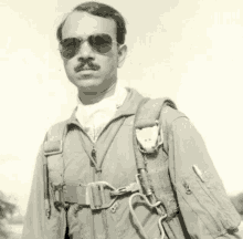 a black and white photo of a man wearing a jumpsuit and sunglasses