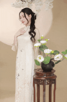 a woman standing next to a vase of white flowers