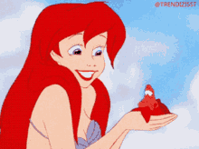 a cartoon of ariel from the little mermaid holding a small lobster