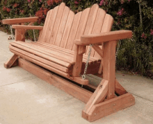 a wooden porch swing with chains attached to it is sitting on the sidewalk .