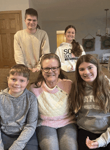 a woman wearing a sweatshirt that says so duet competitors sits on a couch with her family