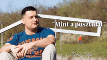 a man in a blue shirt is sitting in front of a sign that says " mint a pusztulat "