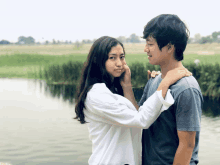 a woman touches a man 's face while they look at each other