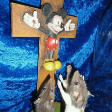 two mice are standing in front of a cross with a mickey mouse statue on it