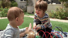 two young boys are playing with a toy in a yard with a sign that says ' amanda ' on it