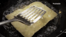 a spatula is being used to stir a piece of cheese in a frying pan ..