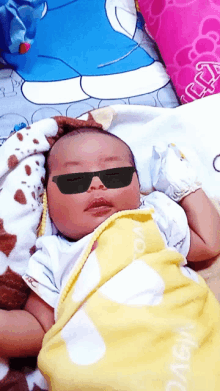 a baby wearing sunglasses is wrapped in a blanket that says ' maya ' on it