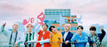 a group of young men are standing next to each other on a balcony holding up balloons .