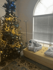 a christmas tree with blue and gold decorations is in a living room