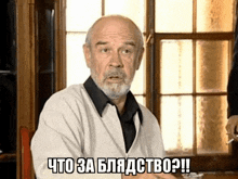 a man with a beard is sitting in front of a window and says " что за блядство ? "