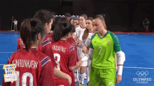 a group of female soccer players are lined up on a blue field and one of them has the number 2 on her shirt