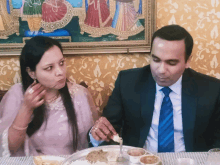 a man and a woman are sitting at a table eating