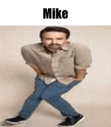 a man with a mustache is standing on his knees with his hands in his pockets and a caption that says mike .