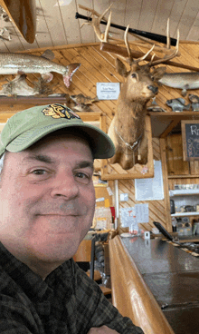 a man wearing a green hat with a tiger on it takes a selfie