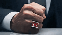 a man in a suit has a ring on his finger that says ' c ' on it