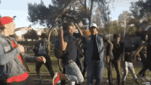 a group of young men are dancing in a park with one wearing a hat that says ' a ' on it