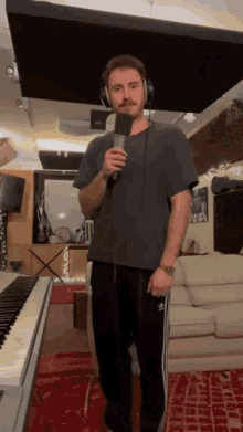 a man wearing headphones is singing into a microphone in a living room