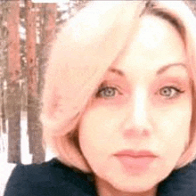 a close up of a woman 's face in front of a snowy forest .