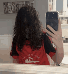 a woman is taking a selfie in front of a mirror with her phone .