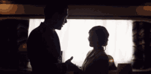 a man and woman are standing in front of a window