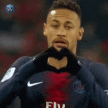 a soccer player making a heart shape with his hands .