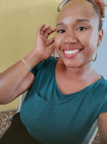 a woman wearing a green shirt and hoop earrings is smiling