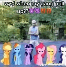 a man is standing next to a group of ponies on a street .