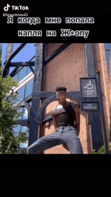 a man is standing in front of a brick building with a sign that says ' smoking area ' on it