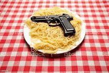 a plate of spaghetti and a gun on a red and white checkered table cloth .