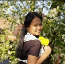 a woman is holding a yellow flower in her hand and smiling